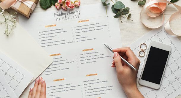 En person planlegger bryllup ved hjelp av en sjekkliste og kalender på et skrivebord.