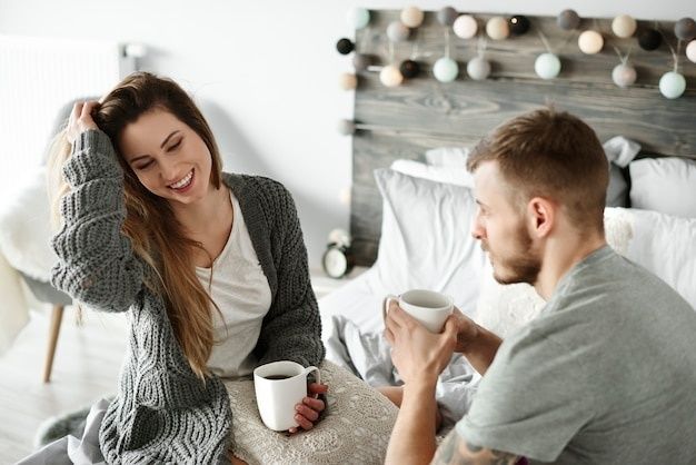 Par drikker kaffe sammen i sengen under en rolig morgenstund