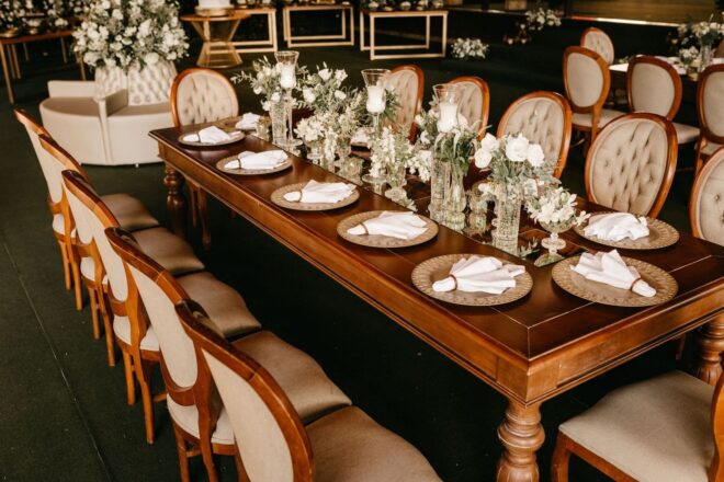 Elegant bryllupsbord med blomster, kuverter og polstrede stoler